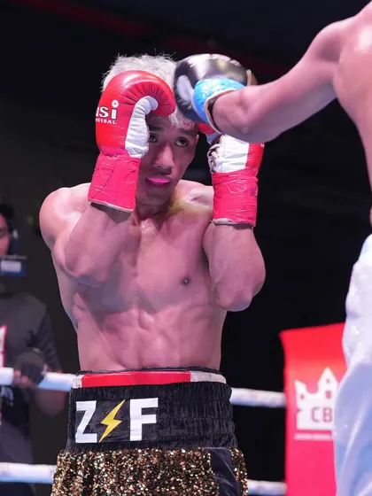 A close-up of a fighter blocking a punch, demonstrating the defensive skill and focus required at this level.