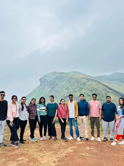 The group posing on the trail, with the unique shape of the Chikmagalur peaks behind them.