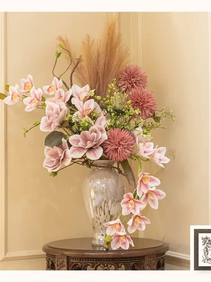 This beautiful arrangement of pink orchids and chrysanthemums adds a soft, romantic touch to this side table. The lifelike quality of the flowers ensures they brighten the room all year round.