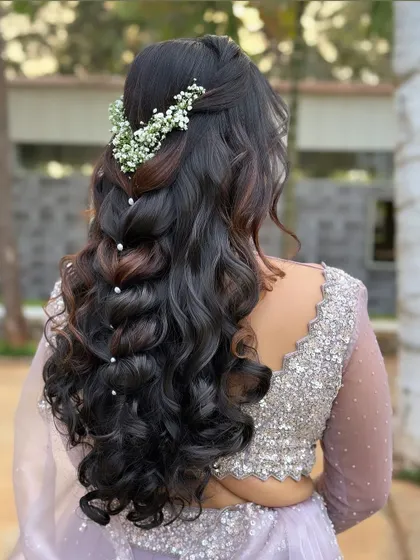 A beautiful half-up style with a braided element and soft waves. The look is adorned with baby's breath and scattered pearls for a romantic finish.