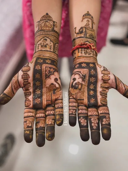 A heavy and intricate design for the mother of the groom. The pattern includes a doli scene and other traditional elements.