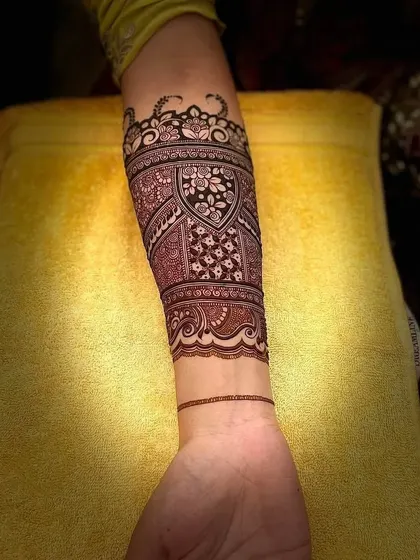 This design features a beautiful cuff-style pattern on the arm, with a shield-like motif filled with intricate details.