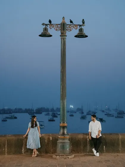 The magic of Mumbai at dusk provides a cinematic setting for romance. This shot at the Gateway of India uses the moody blue hour and iconic lamppost to frame the couple, creating a sense of quiet intimacy within the bustling city.