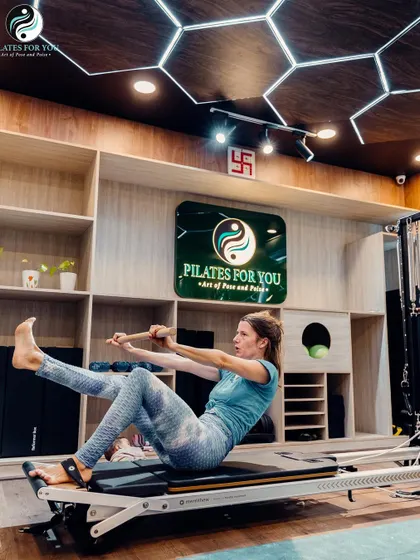 A client performs a challenging core exercise on the Reformer, demonstrating the strength and control developed through consistent Pilates practice.