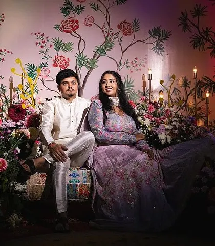 The couple posing on the custom-decorated Mehendi stage. The lighting and floral arrangements create a romantic and festive mood.