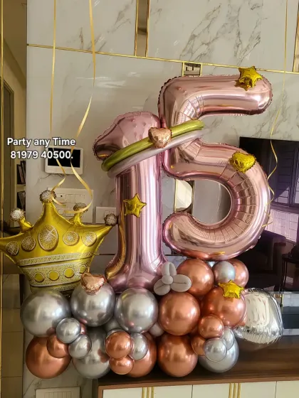 A royal-themed 15th birthday bouquet with rose gold numbers, a large crown foil balloon, and a mix of chrome balloons.