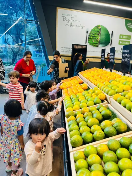 The children are fascinated by the colorful display of oranges and limes at the supermarket.