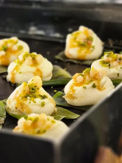A live dessert experience that delights the senses. Our chefs prepare Nolin Gud Pankhi, a traditional sweet, fresh for guests, topping the delicate bites with pistachio and caramel.