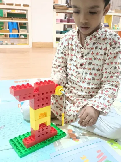 A student concentrates on building a well with a working pulley system, a classic simple machines project.