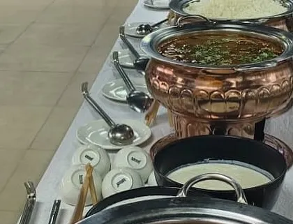 A classic North Indian spread served at a corporate lunch. This setup features our slow-cooked dal, a vegetable curry, and fresh yogurt, served in traditional copper and steel serveware that keeps the food hot and looks professional.