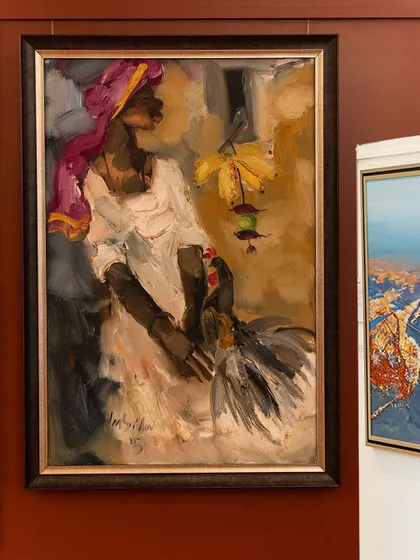 A striking oil painting by M.F. Husain, featured in our 'The Masters & The Modern' exhibition. The piece captures a woman in a pink turban holding a rooster, rendered with the artist's signature expressive and bold brushwork.