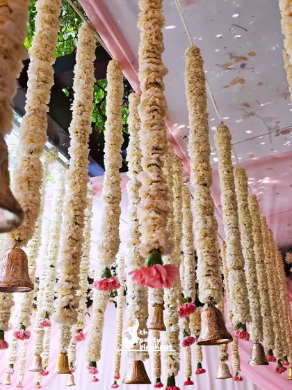 For a traditional touch, I created a ceiling installation of hanging floral garlands, known as 'latkans', made from white flowers and accented with pink carnations and brass bells.