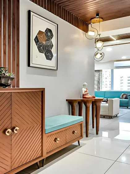 A glimpse into a modern living room from the foyer. The design shows a custom shoe rack with a seating bench, leading into a bright living area with a turquoise sofa.