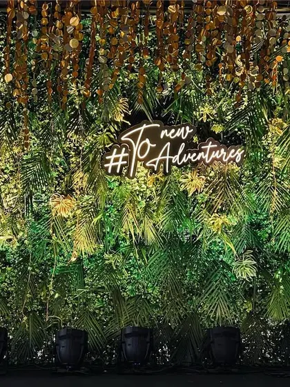 A close-up of the neon sign "To new Adventures" on the lush green backdrop, adding a personal and modern touch.