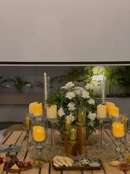 A close up of a romantic tablescape for two. We use a combination of pillar candles in glass holders and fresh white floral arrangements to create a warm, intimate dining experience for the newly engaged couple.