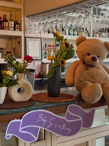 A giant teddy bear and a custom "Baby S is on the way" sign add a personal and adorable touch to the bar area at this baby shower.