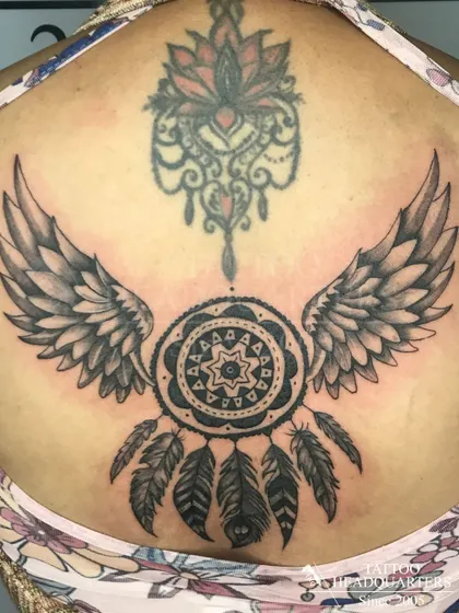 A large backpiece featuring a dreamcatcher with wings, a classic symbol of protection, combined with an ornamental lotus design.