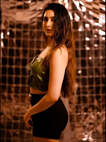 A fashion portrait with a dark, moody vibe. The metallic, reflective background and the wet-hair look create an edgy and modern feel.