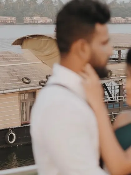 A candid, out-of-focus shot of a couple with Kerala houseboats in the background. This artistic photo captures a quiet, intimate moment during a destination pre-wedding shoot.