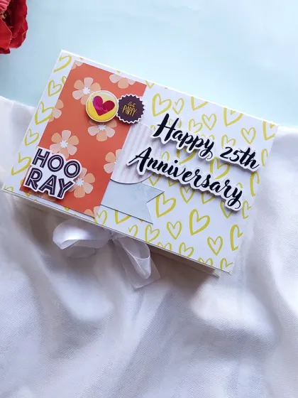 The cover of a "Happy 25th Anniversary" scrapbook, decorated with cheerful patterns and a white ribbon.