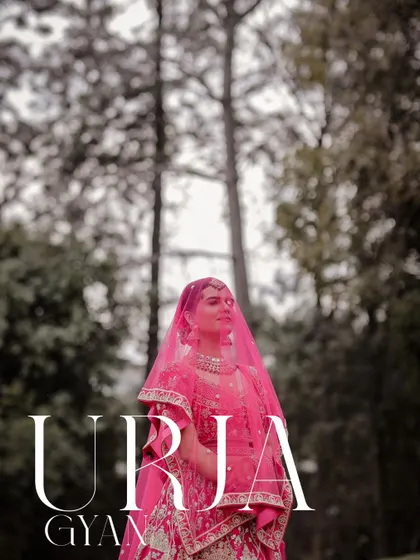 A stunning bridal portrait with a vibrant pink veil against a backdrop of trees.