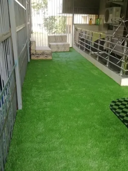 A long balcony area in Gurgaon now covered with lush artificial grass. This makes the space much more inviting for sitting out or for kids to play on.