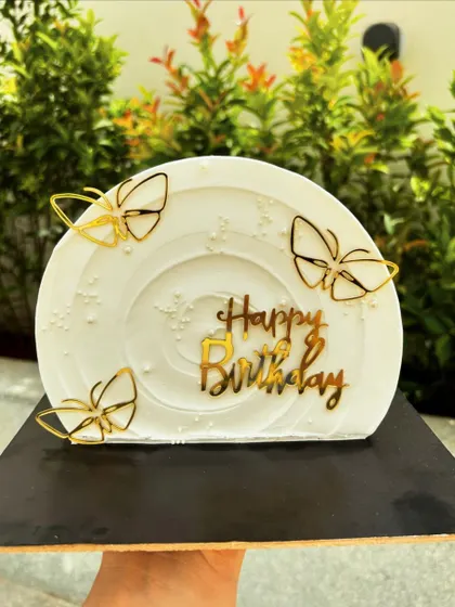 This is a "top forward" cake, where the cake is stood on its side for a unique presentation. The white buttercream is decorated with gold butterfly accents.