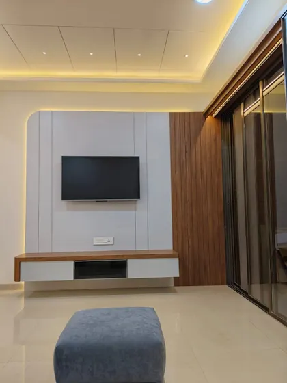 A minimalist TV unit design with a clean white panel and a contrasting wooden side panel. The floating console keeps the floor clear, enhancing the sense of space.