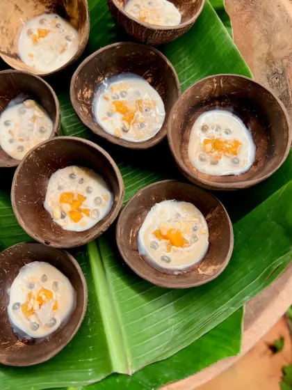 A refreshing tropical dessert of Compressed Melon, Lychee, Shaved Ice & Caramelized Coconut Milk, served in natural coconut shells.