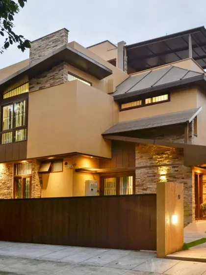 This modern rustic home, known as the 'Mountain Abode', captures the feeling of a mountainside retreat. The exterior lighting design highlights the texture of the stacked stone and the clean lines of the metal-clad roof against the evening sky.