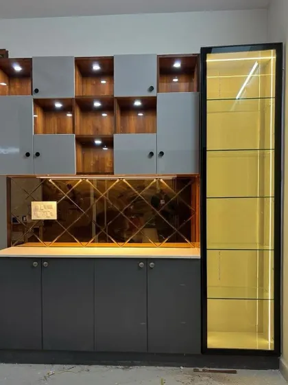 A playful and modern crockery unit design. The asymmetrical open shelves create visual interest, while the glass cabinet and mirrored backsplash add a touch of elegance.