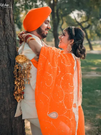 A beautiful, candid moment of a Punjabi couple sharing a hug. The bride's vibrant orange suit and traditional kaleere add a wonderful cultural element to the shoot.