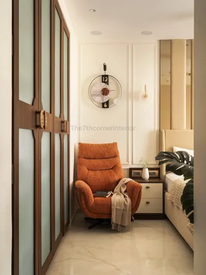 This cozy reading nook features a plush lounge chair set against an elegant paneled wall. The wardrobe, with its wooden frames and frosted glass panels, adds a refined touch to the serene ambiance.