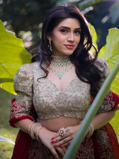 A beautiful portrait of Mahima, a "blooming rose". Her makeup is fresh and radiant, with a soft pink lip that complements the natural, garden like setting.