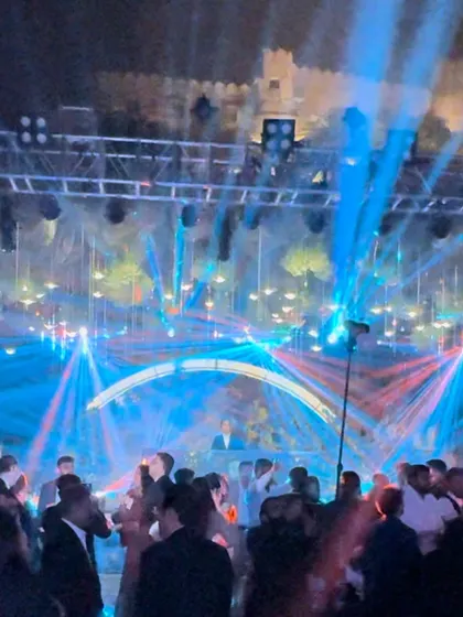 A stunning shot of a reception party set against an ancient fort. The vibrant blue and red lights create a modern contrast with the historic setting, making for a truly unique visual experience.