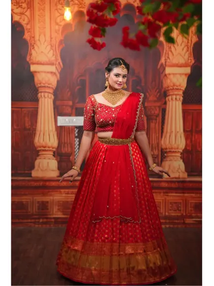 Our hand-embroidered red half-saree is perfect for a bridal or festive look. The rich red color and gold detailing are timeless.