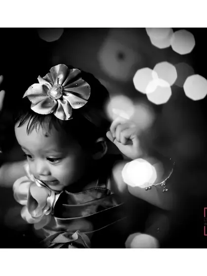 An artistic black and white photo of the birthday girl, with a shallow depth of field creating a beautiful bokeh effect from the party lights.