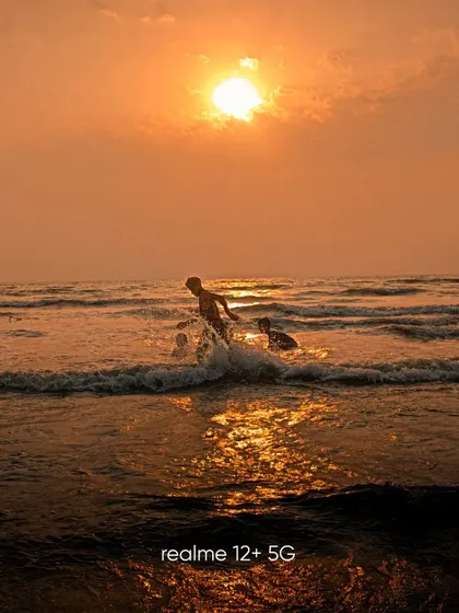 Capturing the action of children playing in the waves at sunset. The warm light and splashing water create a dynamic and joyful scene.