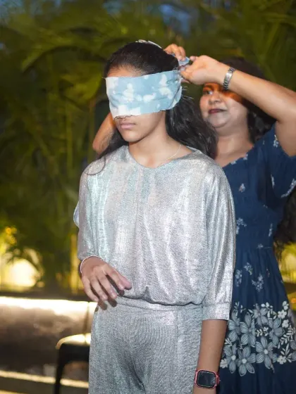 Getting a young guest ready for a blindfold game at a Gen-α birthday party. I make sure every participant feels comfortable and excited to join in on the fun activities.