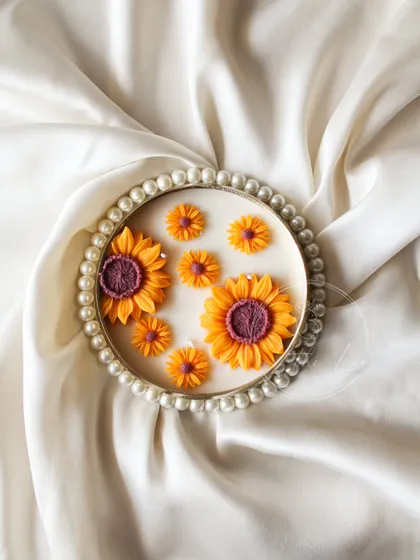 The pearl-rimmed Sunflower Urli, looking elegant on a satin cloth. This piece is all about simple luxury and the beauty of nature.