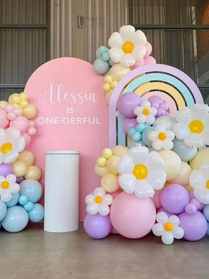 A "one-derful" first birthday party with a daisy and rainbow theme, using pastel balloons to create a cheerful and sweet atmosphere.