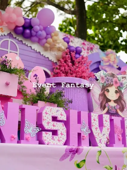 A detailed shot of the "NISHVIKA" name blocks, decorated with a floral pattern and butterflies, sitting in front of the whimsical fairy house.