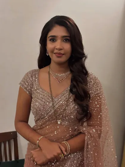 A client looking elegant in a sequined saree with her hair in soft, side-swept waves.