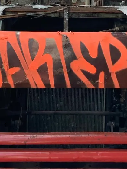 A bold orange throw-up on the front of a burnt-out truck. Finding unique spots and surfaces is part of the game.