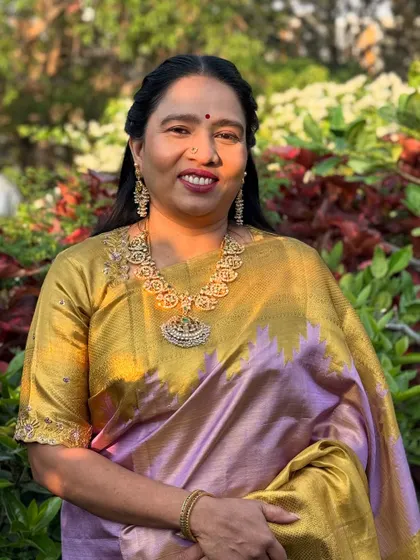 The mother looks absolutely graceful in her gold and lavender Kanchipuram silk saree. Her makeup is classic and elegant, enhancing her features beautifully.
