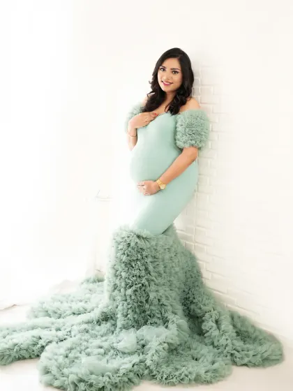 A relaxed and happy portrait. Leaning against the wall, this mom-to-be's smile lights up the frame, showing off the beautiful off-shoulder design of the gown.