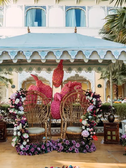 The couple's seating with peacock-style wicker chairs and elaborate floral arrangements, fit for royalty.