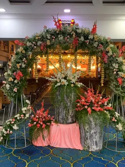 A beautiful floral archway for a naming ceremony, filled with pink, white, and peach flowers, creating a perfect frame for the main event area.