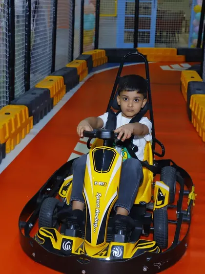 A focused young driver in a yellow go-kart, enjoying the thrill of being in control.