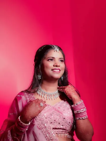 A vibrant solo portrait of the bride against a bright pink background. Her joyful, upward glance and beautiful diamond jewelry are the focus of this modern and stylish shot.